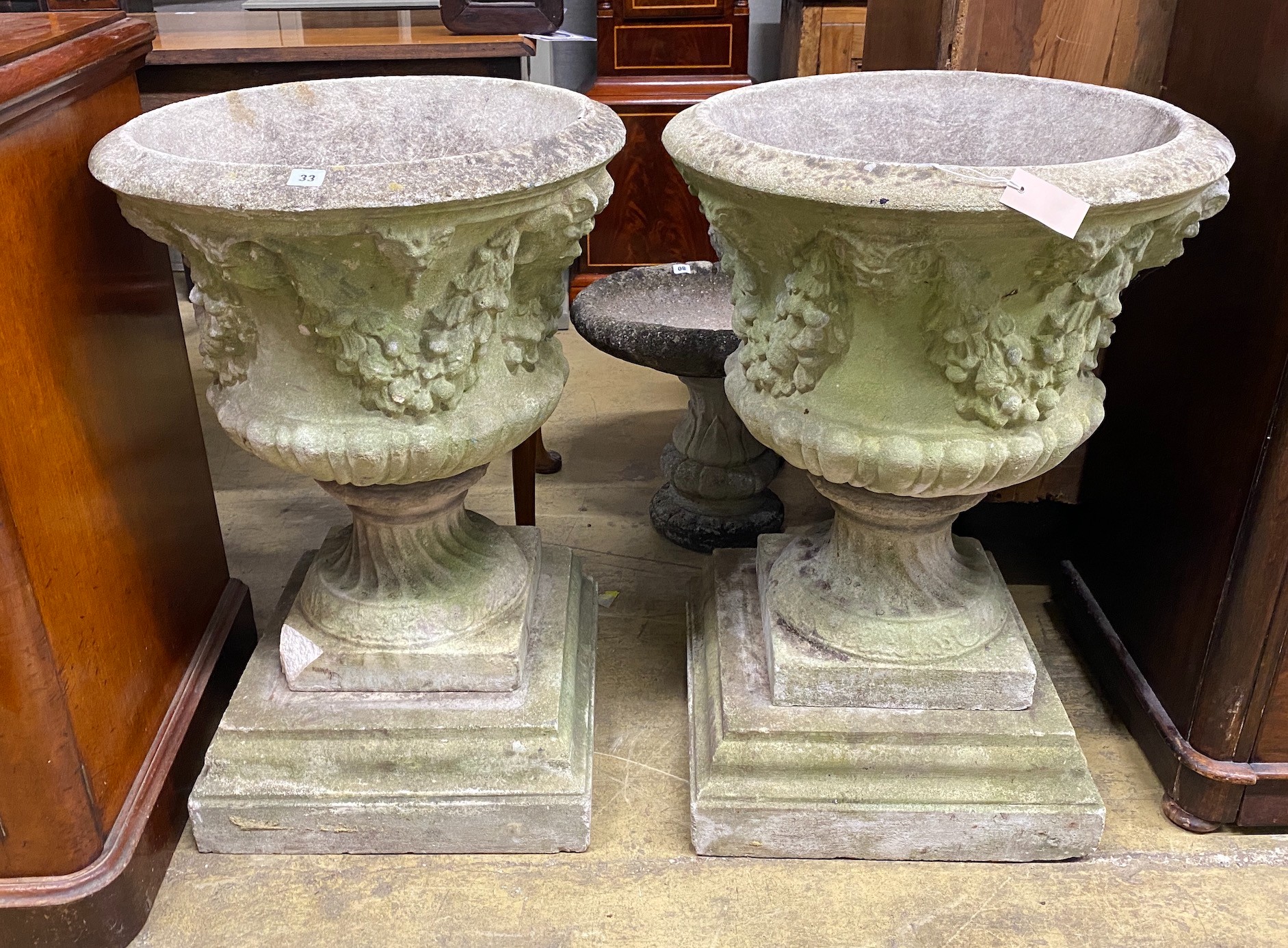 A pair of circular reconstituted campana garden urns with floral swagged bodies, diameter 59cm, height 86cm